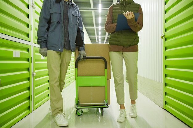 Man carrying trolley and woman making notes in document while they walking along the corridor