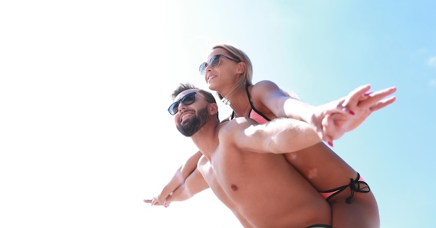 Man carrying woman piggyback on beach