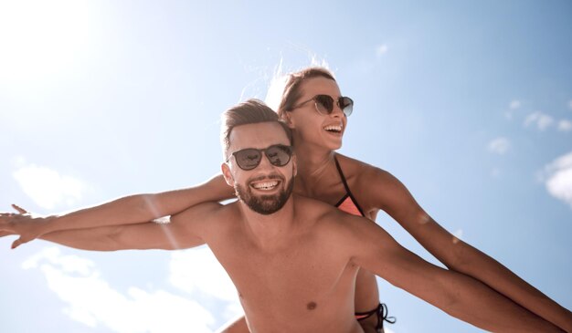 Man carrying woman piggyback on beach