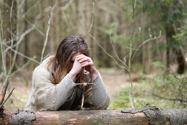 A man in a cassock spends a ritual in a dark forest with a crystal ball and book