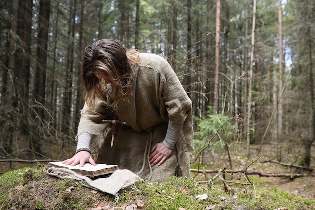 A man in a cassock spends a ritual in a dark forest