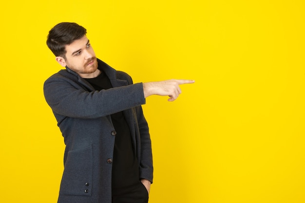 Foto uomo in abiti casual che punta il dito lontano.