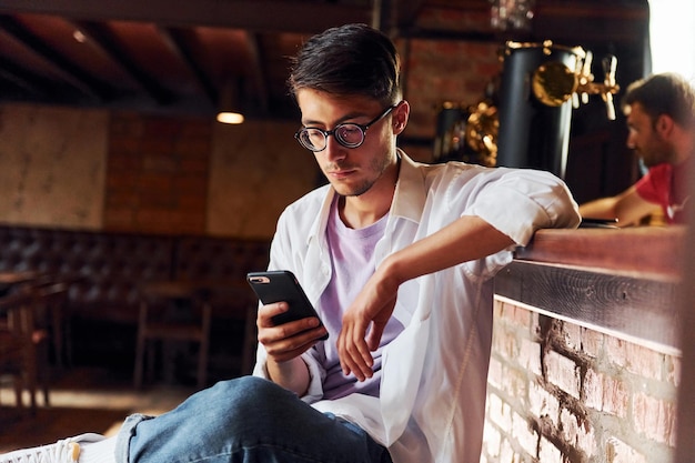 Uomo in abiti casual seduto al pub durante il giorno