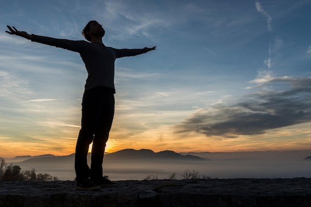 Man in casual clothes with his arms spread widely standing outdoors