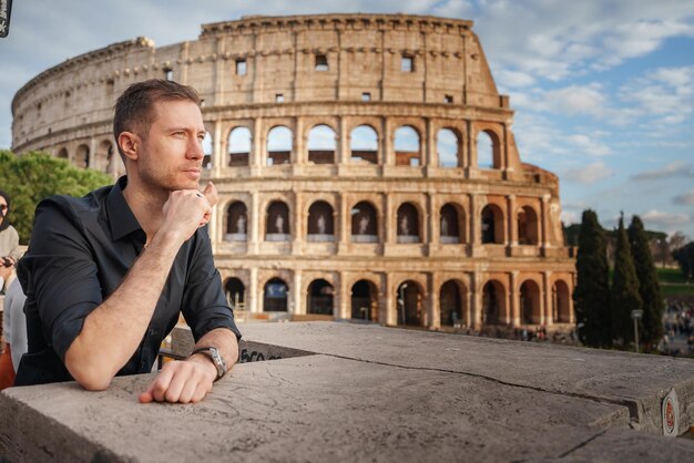 Photo man in casual shirt admires colosseum view in rome italy