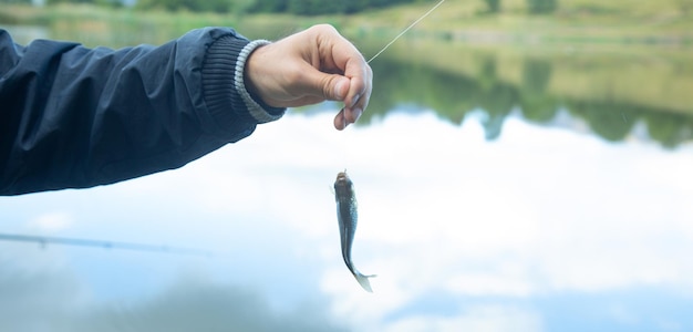 写真 湖で小さな魚を捕まえて見せている男