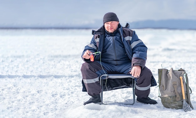 穴の氷の上で魚を捕まえる男