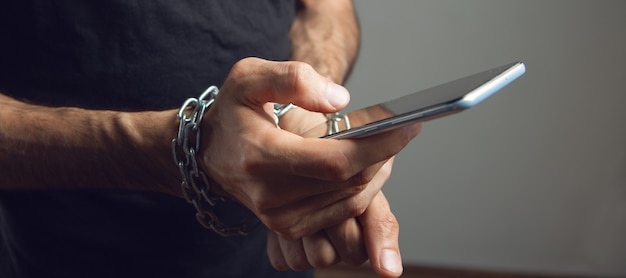 Foto un uomo in catene con in mano un telefono