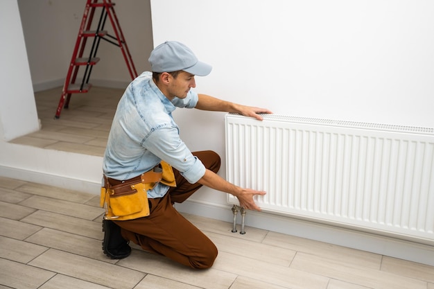 A man changes the heating in the house, radiators. the concept\
of modern heating, replacement of the old with a new one. warmth in\
the house