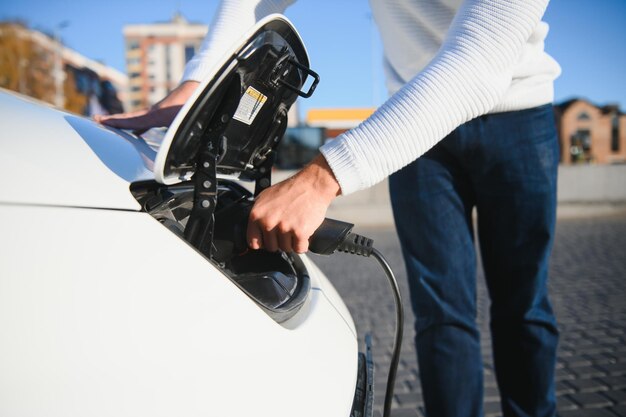 L'uomo carica un'auto elettrica alla stazione di ricarica