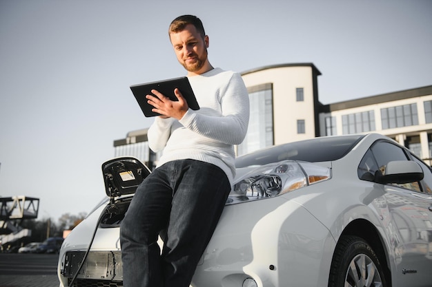 Man charges an electric car at the charging station