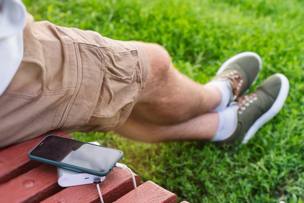 Man charges a smartphone with a power bank in hand. Portable charger for charging gadgets.