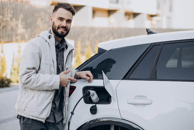 Man charging electric car by the house