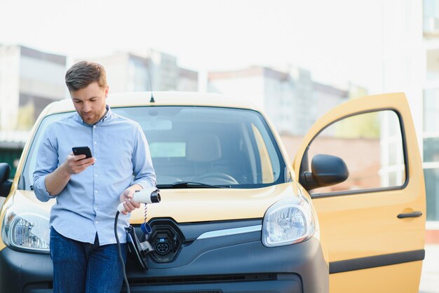 家のそばで電気自動車を充電する男