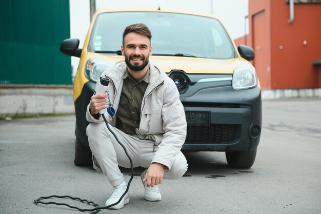 Man charging electric car by the work