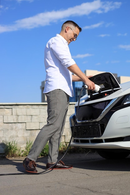 Foto uomo che carica un'auto elettrica in una stazione di servizio elettrica