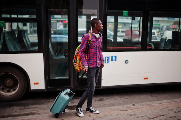 Man in checkered shirt, with suitcase and backpack