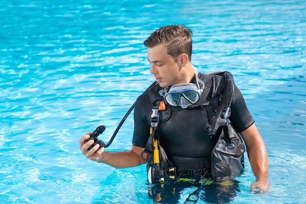 プールに立っている間に空気調整器をチェックする男