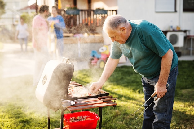 Man checking on grill in his backyard.