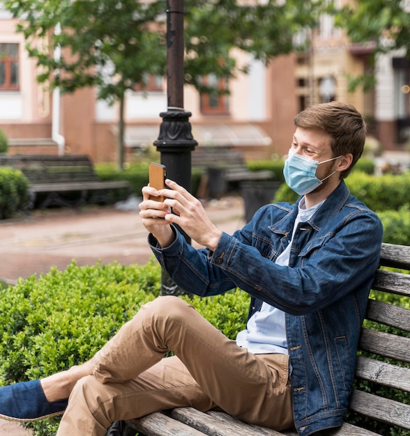 Photo man checking his phone while wearing a face mask with copy space