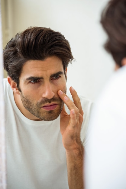 Man checking his skin in bathroom