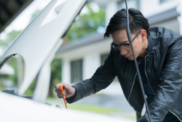 車のオイルレベルをチェックする男はオイルカーを交換します