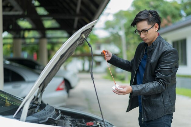 車のオイルレベルをチェックする男はオイルカーを交換します