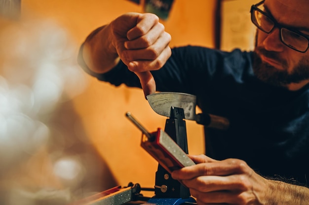 Foto uomo che controlla una macchina per coltelli affilati in officina