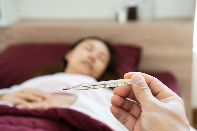 Man checking temperature of his sick wife