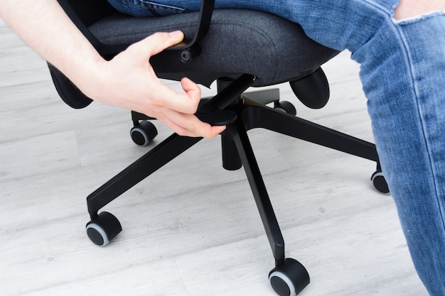 Photo man checks lifting mechanism of chair assembling office chair indoors