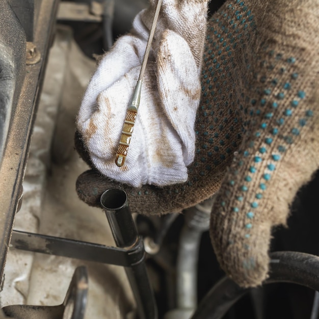 A man checks the oil level in a car engine after changing it closeup