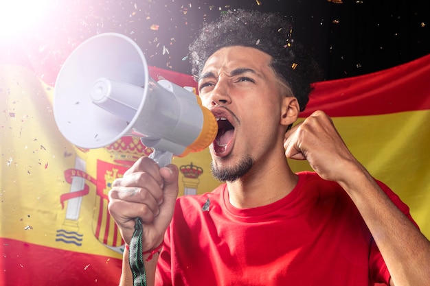 写真 スペイン国旗のメガホンで応援と話す男