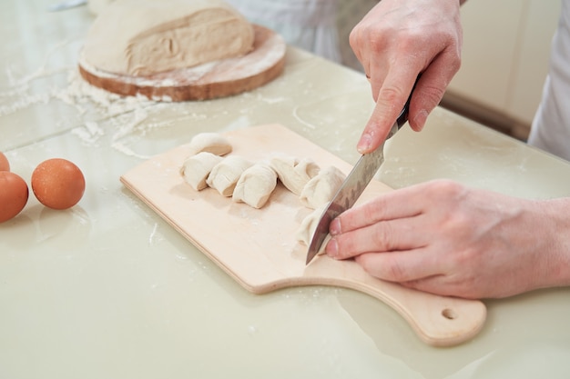 Man chef cuts the dough into pieces