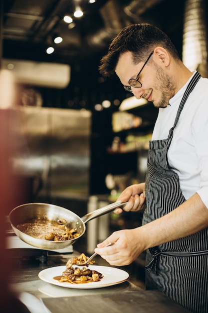 Man chef-kok koken Aziatische kip in een café-keuken