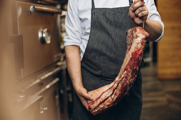 Man chef-kok met een groot deel van het vlees in de keuken van het restaurant