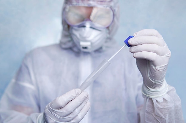 A man in a chemical protection suit holds a test tube for analysis. COVID-19. Coronavirus swab sample COVID-19. swab coronavirus test. Used Transport Bag. Epidemic outbreak