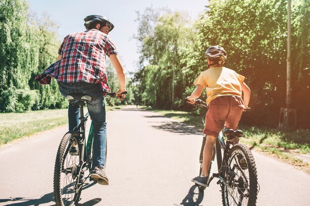 男と子が一緒に道路で自転車に乗っています。