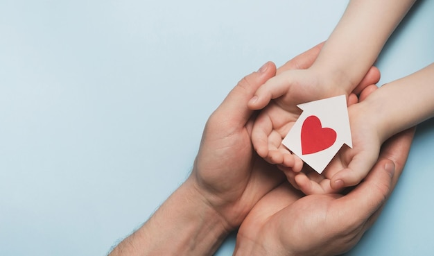 Photo man and child holding miniature house with heart family love safety and healthcare