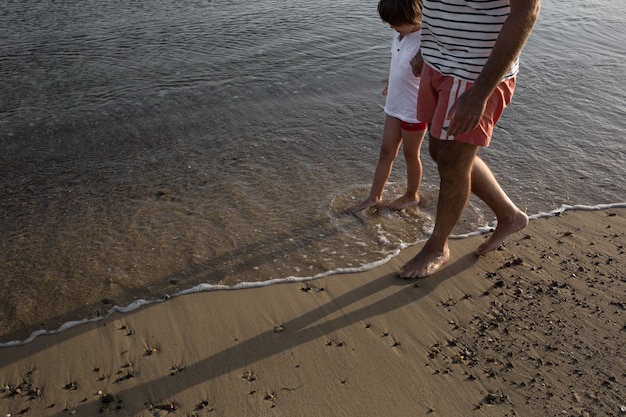 Photo man and child walking at the beach together