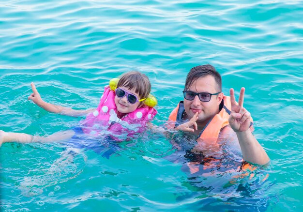 Foto un uomo e un bambino che indossano occhiali da sole galleggiano nell'acqua