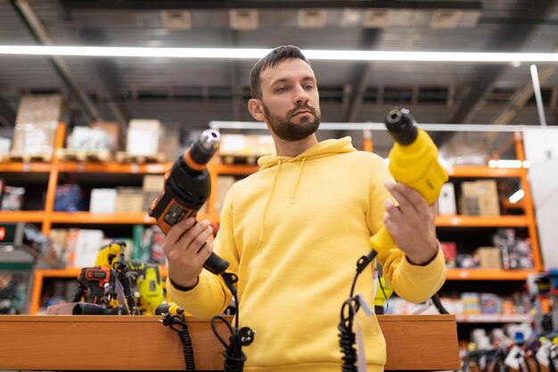 A man chooses a drill for himself as a gift in a construction equipment store