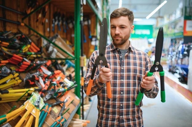 Photo a man chooses garden shears in a hardware store