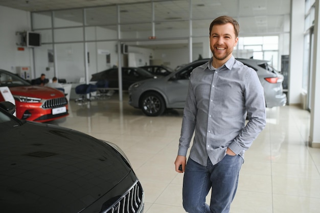 A man chooses a new car for himself walks between the rows in a car dealership