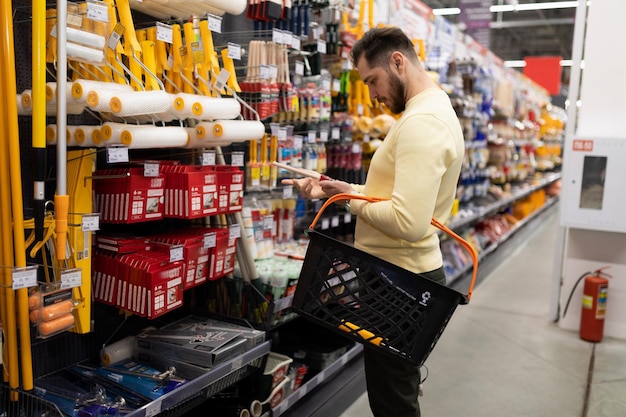 Photo a man chooses a tool for painting work in a decorating materials store