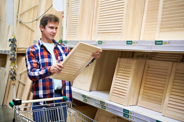 Photo man chooses wooden facades for furniture in store