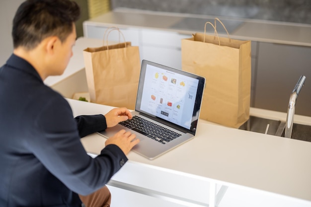 Man choosing groceries in online store on laptop