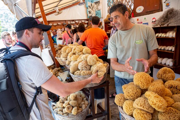 Man choosing natural sea sponge sold on a market on Symi Island Greece