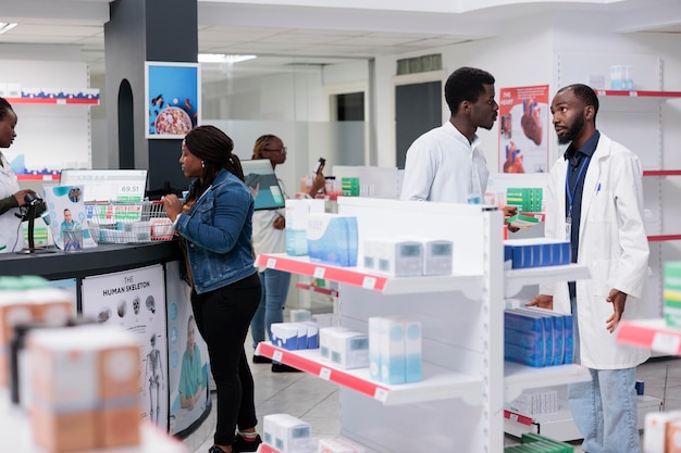 Man choosing vitamins in drugstore, woman buying prescription treatment on checkout counter. African american customers purchasing medicaments in pharmacy store, pharmacist recommending pills