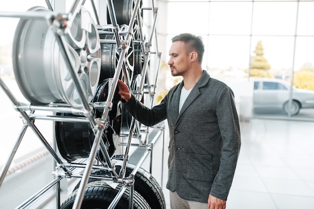 Uomo che sceglie ruote per auto nuove in showroom.