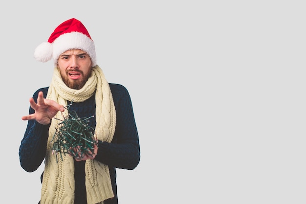 灰色の背景にクリスマスの帽子をかぶった男